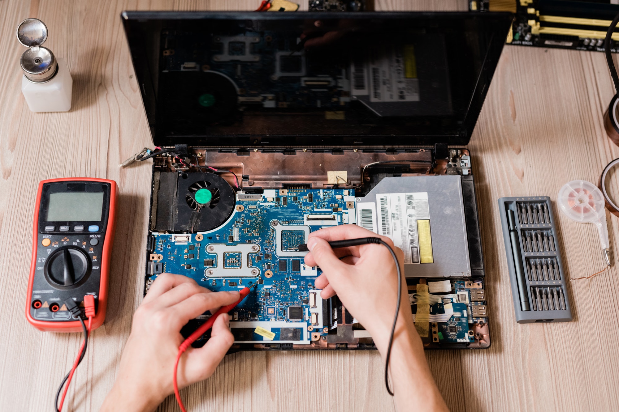 Hands of contemporary master using small soldering-irons to repair broken laptop